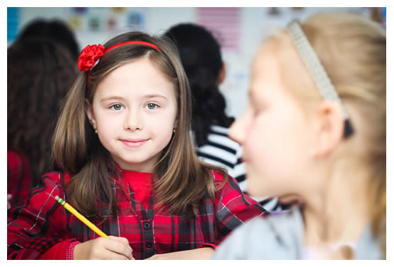2 special needs girl students sitting at desks in a school classroom