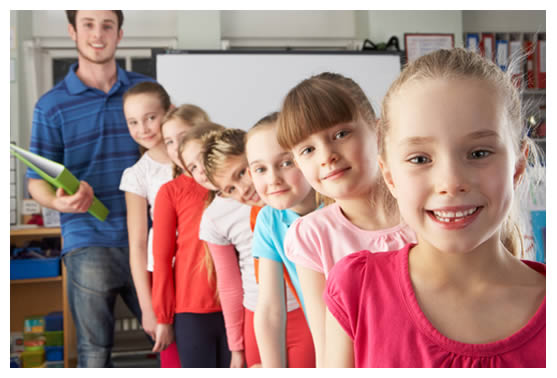 7 special needs students and young male teacher all smiling at you and standing in a line at school
